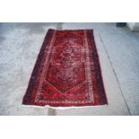 A red woven rug, worn to the centre, 73" x 42 1/2".