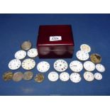A square cigarette box containing 19 pocket watch movements for spares/repairs and three watch