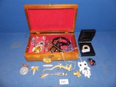 A wooden jewelry box containing assorted jewellery, necklaces,a lizard brooch, pendants,
