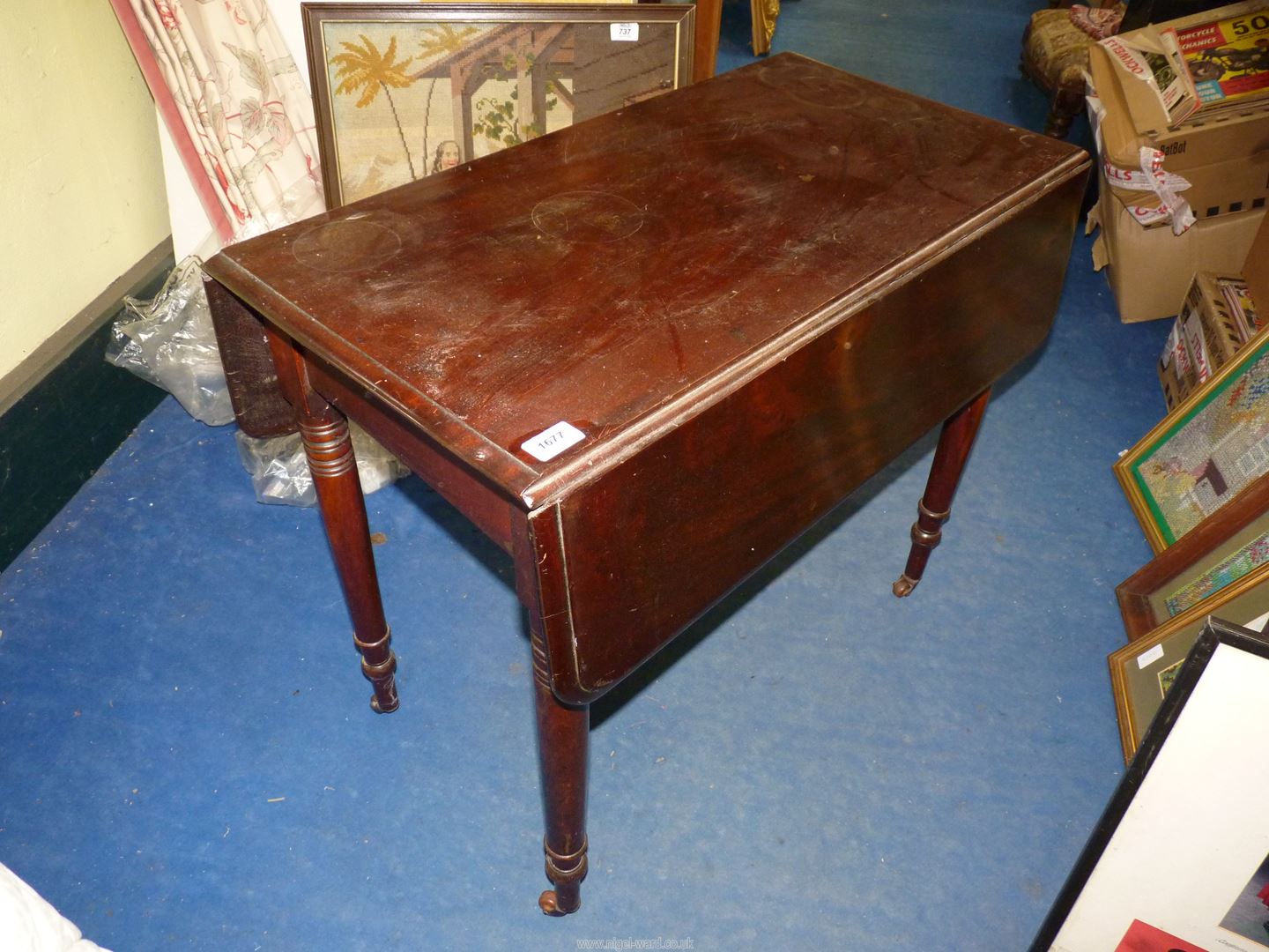 A heavy dark Mahogany Pembroke Table standing on turned legs with brown china castors and having a