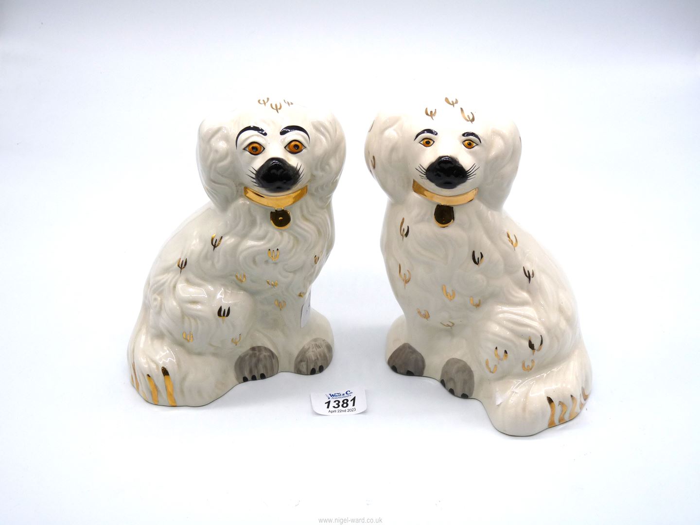 A pair of Staffordshire style white mantle Spaniels with gold collars and padlocks, with grey paws,