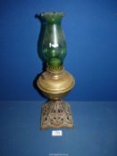 A Oil lamp with cast metal base, brass reservoir and green chimney, 17" tall.