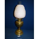 An Oil lamp with brass base having pale pink pressed glass shade with floral motifs (chip to rim),