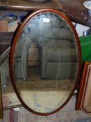 An oval mahogany framed bevelled wall mirror, 31 1/2" high x 19" wide.