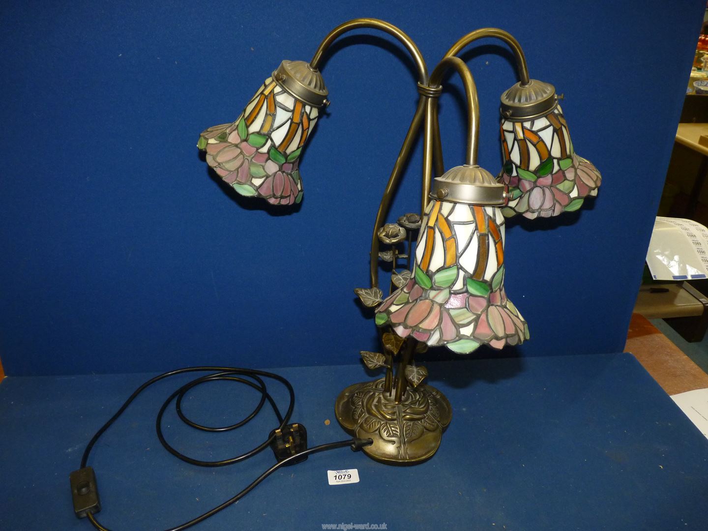 A three branch contemporary Tiffany style table lamp with three floral shades in pinks and green,