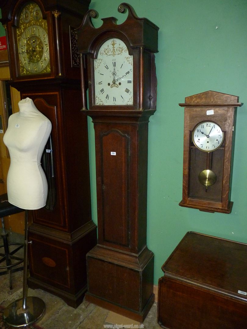 A cross-banded Oak cased Longcase Clock having a painted face with Roman hour numerals and Arabic