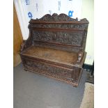 A profusely carved Oak Hall locker base Settle, the backrest with depictions of Phoenixes,