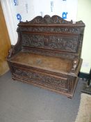 A profusely carved Oak Hall locker base Settle, the backrest with depictions of Phoenixes,