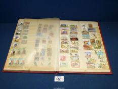 A red Stamp stock book with miscellaneous stamps and a few postcards.