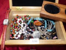 A wooden jewellery box containing a selection of costume necklaces, brooches, etc.