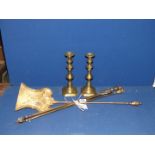 Three brass fire irons and a pair of brass candlesticks.