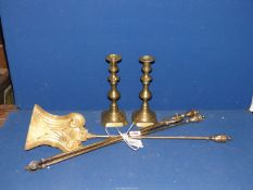 Three brass fire irons and a pair of brass candlesticks.