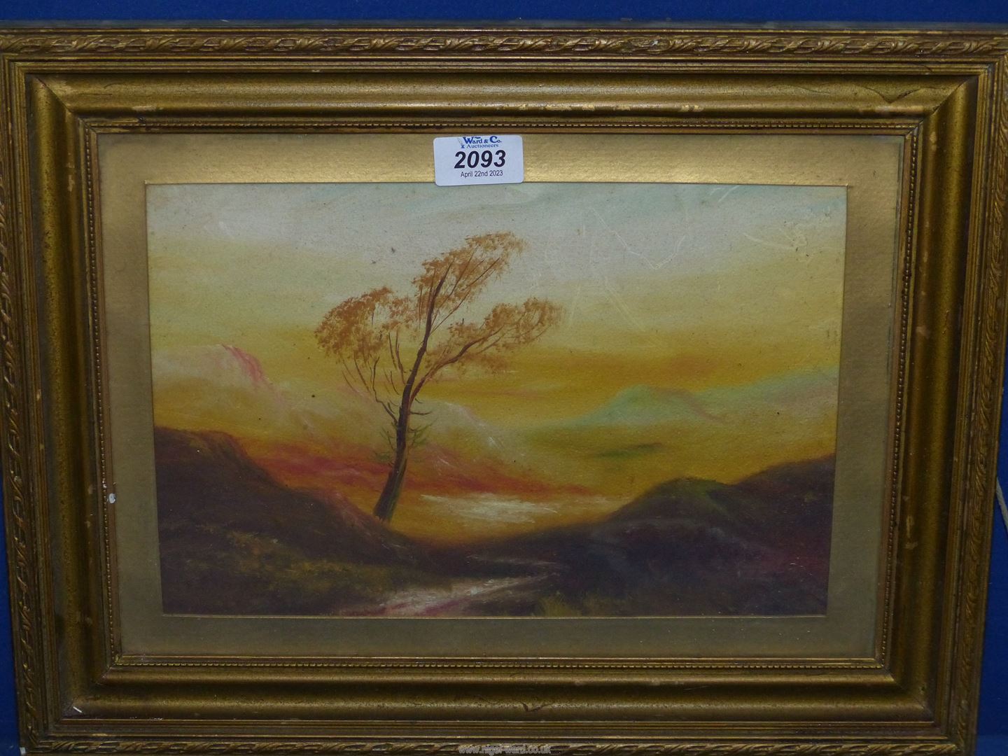 A small gilt framed Oil painting depicting a lonely tree on a mountain side with rolling hills and