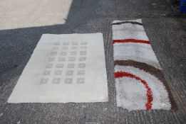 A red/brown/beige runner 25" x 90" and beige rug with square pattern 46" x 65".