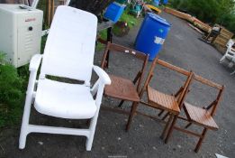 Three folding wooden chairs and a white plastic garden seat.