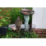 A concrete birdbath and wire planters in the form of a waiter and a bike.