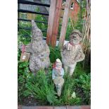 Two gnomes including one on a bike, larger one sitting and another garden statue.