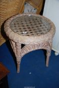 A circular wicker table with glass top, 22" diameter x 22 1/2" high.