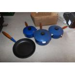 A set of three blue Le Creuset saucepans and frying pan.