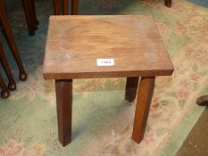 A rectangular topped Stool of primitive design with through-mounted square legs,