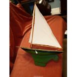 A model of a sailing yacht with green metal base, hull sails stained, 25'' long x 18 1/2'' high.