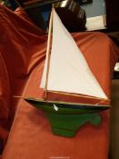 A model of a sailing yacht with green metal base, hull sails stained, 25'' long x 18 1/2'' high.