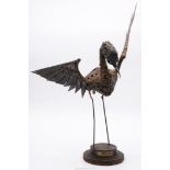 A heavy metal "Walenty Pytel" Bird sculpture having outstretched wings on a raised stepped circular