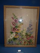 A framed tapestry of cottage garden flowers including hollyhocks, etc.