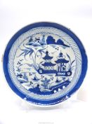 An Oriental plate in blue & white scenes of Pagoda's and cottage by water with small boats,