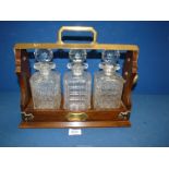 A wood and brass Tantalus with three matching cut glass decanters (some chips to bases).
