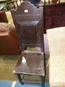 A dark Oak high back Hall Chair having a solid seat and raised and fielded panel to the back,
