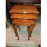 A Nest of Three Serpentine edged Satinwood Occasional Tables standing on cabriole legs,