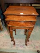 A Nest of Three Serpentine edged Satinwood Occasional Tables standing on cabriole legs,