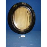 A small oval Victorian mirror, with black gloss and gilt frame.