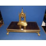 A brass Gothic picture frame and a brass hot plate.