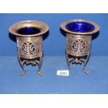 A pair of Art Nouveau silver plated pierced Salts on three paw feet with blue glass liners (one