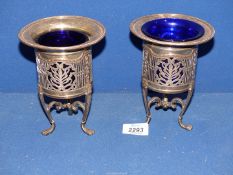 A pair of Art Nouveau silver plated pierced Salts on three paw feet with blue glass liners (one