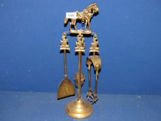 A small brass companion set having horse hunting themed finials, complete with tongs, brush,