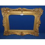 An ornate Victorian gilt gesso swept frame in need of restoration, aperture 17 1/4'' x 11 1/2''.