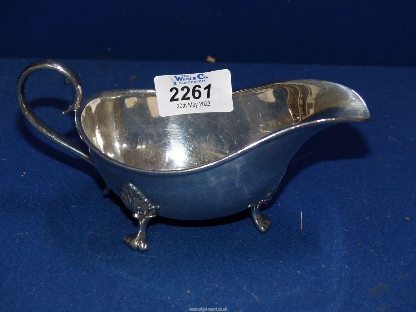 A Silver sauce boat, London 1926 by Kemp brothers, standing on three paw feet.