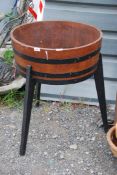 A wooden barrel planter on three wooden legs, 23'' diameter x 29 1/2'' high overall.