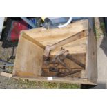 A wooden box with log splitter, pickaxe head, hammer etc.