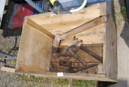 A wooden box with log splitter, pickaxe head, hammer etc.