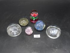 Six paperweights including plain clear glass, mauve swirl, pink flower etc.