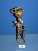 An African metal figure in the shape of a woman with a staff and carrying a child on her back and