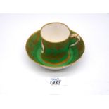 A Sevres coffee can and saucer painted with floral cartouches against an apple green ground