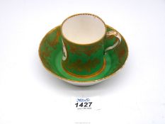 A Sevres coffee can and saucer painted with floral cartouches against an apple green ground