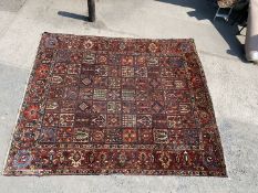 A Baktiari Rug with blue, green and yellow tile effect pattern on red ground, some wear and tear,