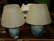 A graduated matched pair of blue and white oriental Lamps with scenes of fishermen by the sea with