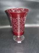A large ruby vase with clear glass footed base, the body engraved with star style design.